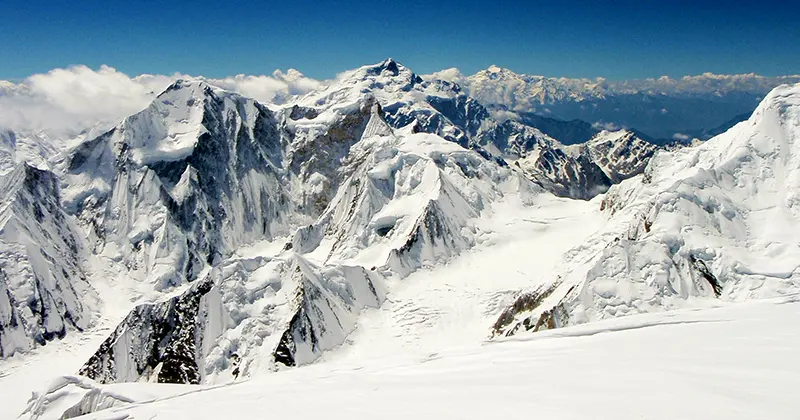Met sneeuw bedekte bergtoppen onder een helderblauwe hemel, met ruige bergkammen en diepe valleien, die samen een indrukwekkend en weids alpenlandschap vormen.